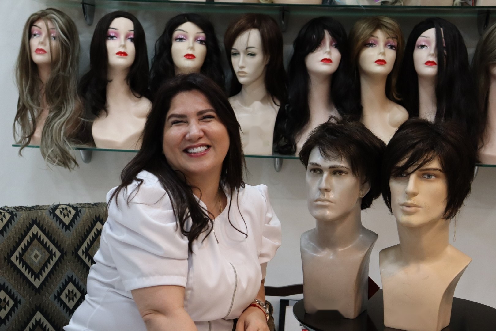 Cristina Orosa sonriendo entre la colección de pelucas premium de su atelier